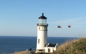 Aircrews aboard MH-65 Dolphin and MH-60 Jayhawk helicopters fly past the North Head Lighthouse located in Cape Disappointment State Park in Ilwaco, Wash., Nov. 7, 2018. The Dolphin and Jayhawk helicopters are the two types of Coast Guard helicopters that are used during search and rescue operations.