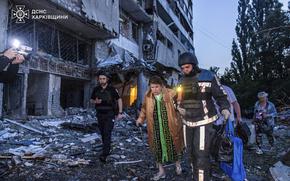 In this photo provided by the Ukrainian Emergency Services on Thursday, June 12, 2025, a rescue worker evacuates a woman from a building which was damaged by a Russian strike in Kharkiv, Ukraine. (Ukrainian Emergency Services via AP)