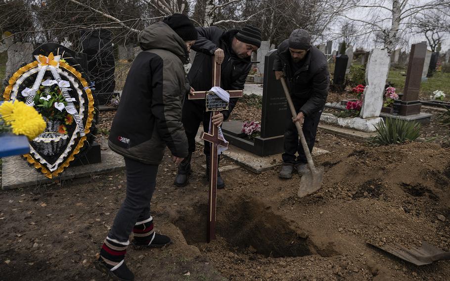 Family members place a cross on the grave of 2-day-old Serhii Podlianov at a cemetery in Novosolone in the Zaporizhzhia region of Ukraine on Nov. 24, 2022. 