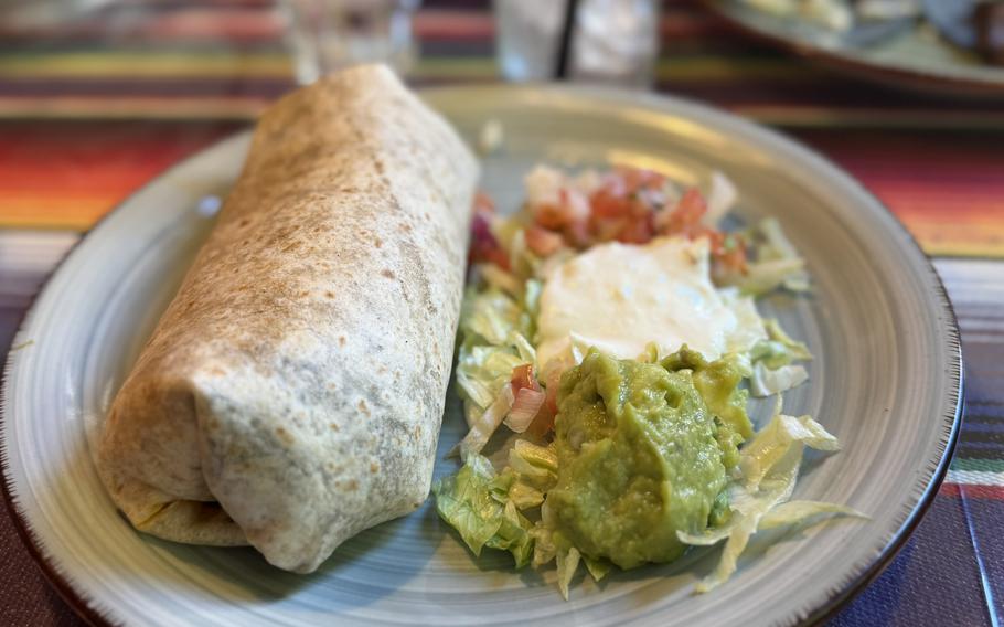 A burrito with condiments ready to eat at a Mexican restaurant.