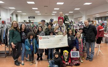 Large group of adults and children holding up a giant check