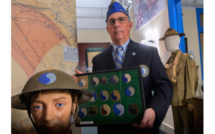 Posing between a mannequin wearing a helmet bearing the blue-and- gray insignia and the uniform of U.S. Army Pvt. Otto J. May from 1918 is Frank Armiger, national executive director of the 29th Infantry Division Association. That group is seeking to preserve the division’s yin yang-style patch. It is under review by a national commission examining military names and symbols. The panel has already recommended renaming Army posts named for Confederate soldiers.