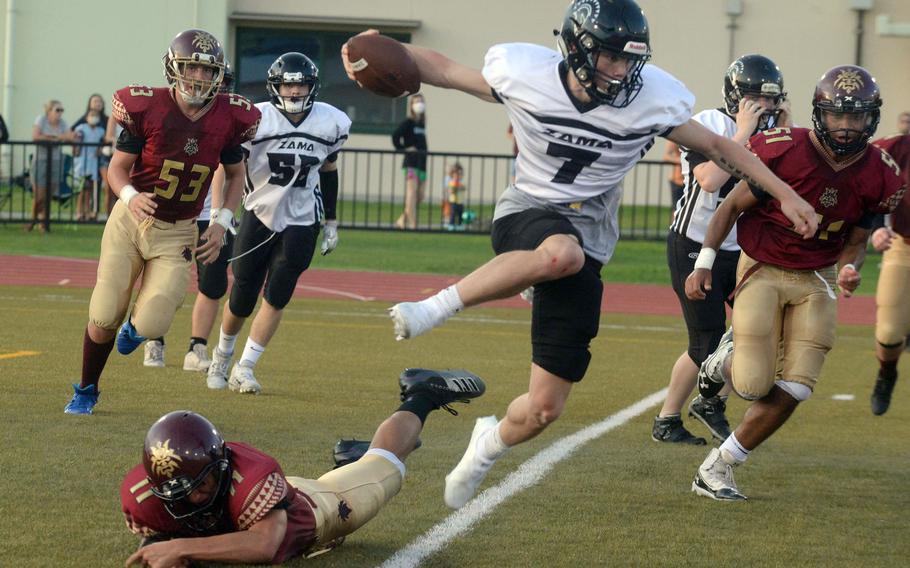 Zama quarterback Dominic Peruccio goes airborne to avoid Matthew C. Perry defenders Nickolas Elizondo and Tyler Ortiz.