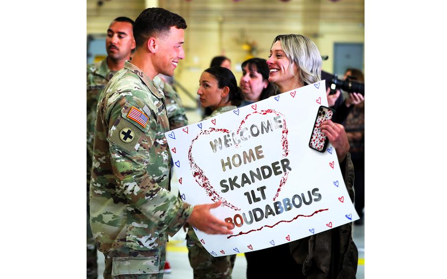 A woman greets a soldier with a sign
