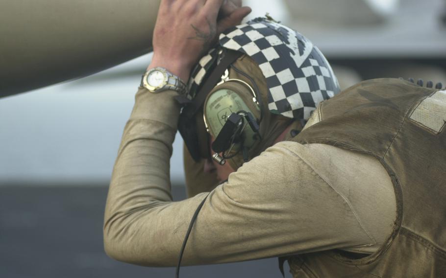 A person rests on the nose of a fighter jet