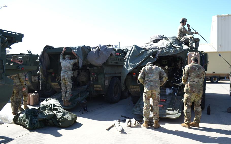 A handful of soldiers working on military vehicles.