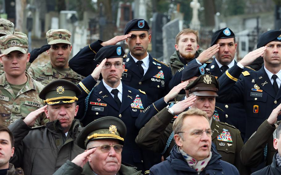 U.S. soldiers salute during a ceremony at Lychakiv Cemetery in Lviv, Ukraine, in December 2021, about two months before Russia’s full-scale invasion of Ukraine. American service members in Ukraine can now earn up to $325 more per month, according to new Pentagon guidance.