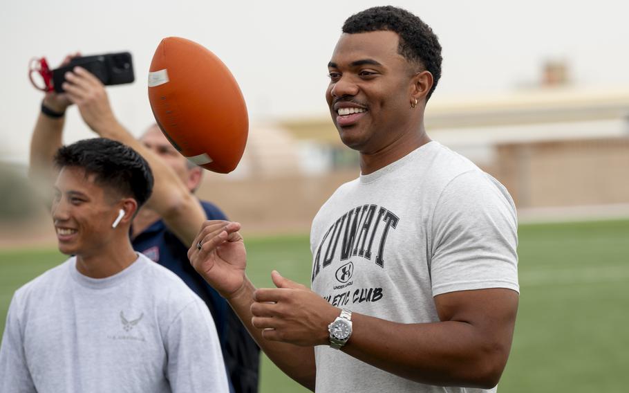 Elijah Higgins smiles and tosses a football in the air