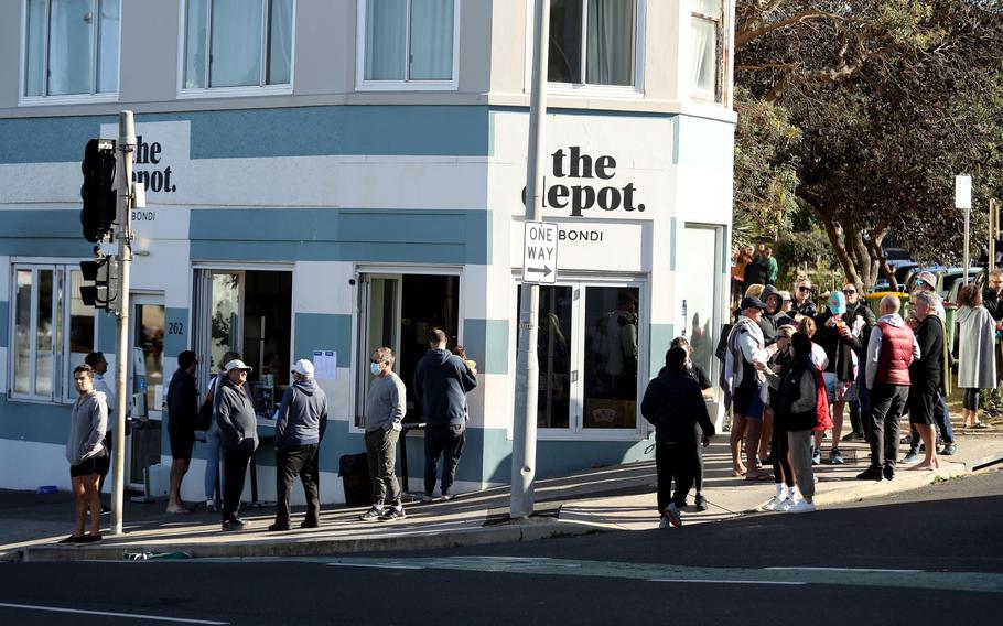 People gather outside a cafe on Bondi Beach for take-away food and beverages in Sydney on July 4, 2021.