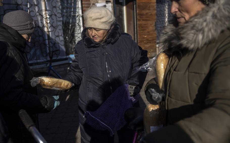 Residents receive loaves of bread distributed by a neighbor in Yampil on Dec. 17.