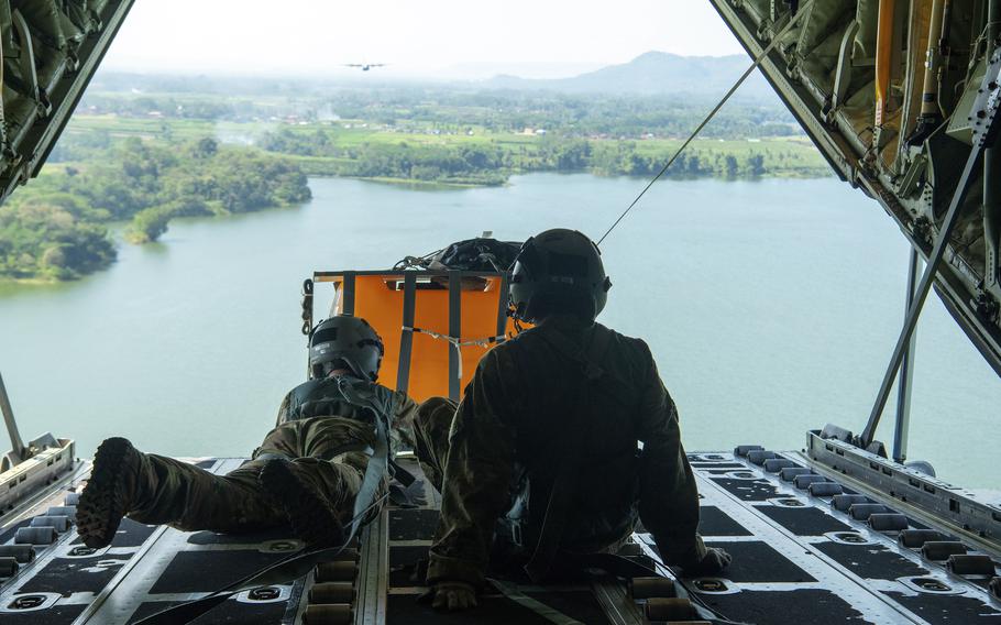 Air Force Staff Sgt. Jay Tuazon, left, and Airman 1st Class Ian Munoz push a bundle out of a C-130J Super Hercules assigned to the 36th Airlift Squadron over Malang, Indonesia, June 20, 2022. 