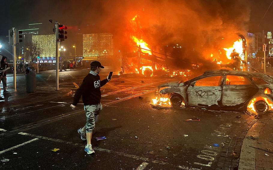 Flames rise from a car and a bus, set alight at the junction of Bachelors Walk and the O'Connell Bridge, in Dublin on Nov. 23, 2023, as people took to the streets in protest following a knife attack earlier in the day. 
