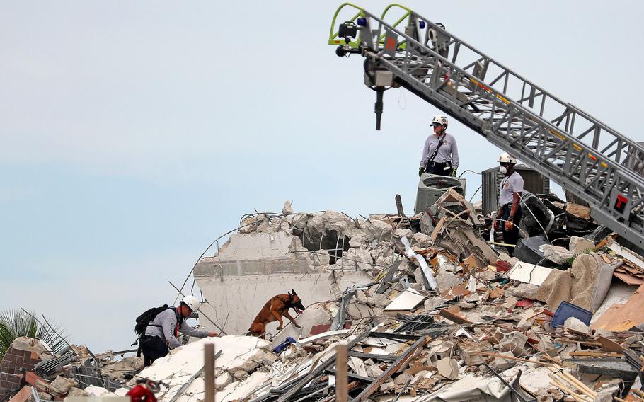 Search and rescue workers along with K-9 units search the site of the 12-story oceanfront Champlain Towers South Condo in Surfside, Fla. 