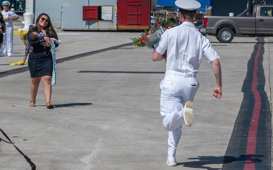 Alex Souter sprints down the dock to wife Daniela Souter as she holds their newborn son, George. He was among seven fathers who got to meet their new babies for the first time as the crew disembarked from the ship.