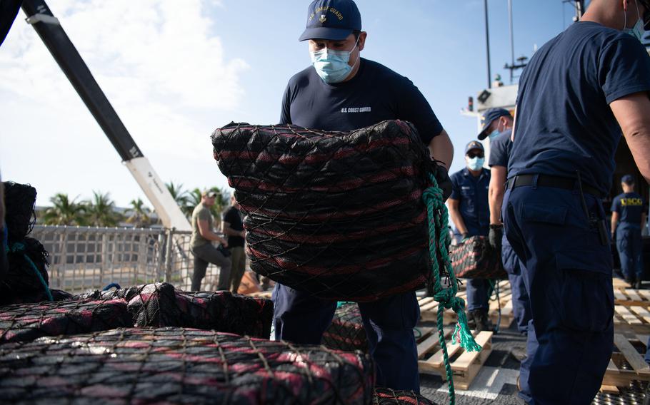 A crew member stacks a bale of cocaine