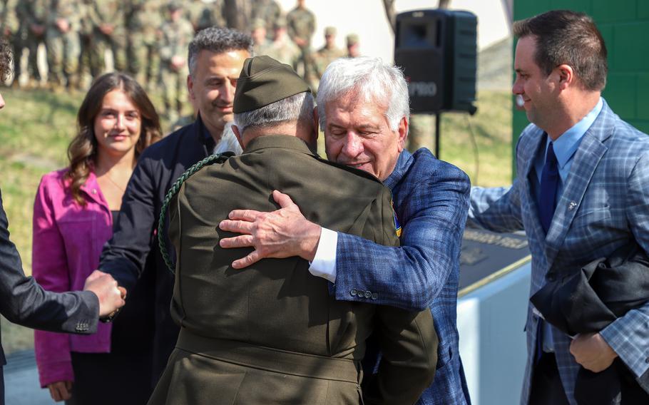 A man with gray hair hugs a general in an Army uniform.