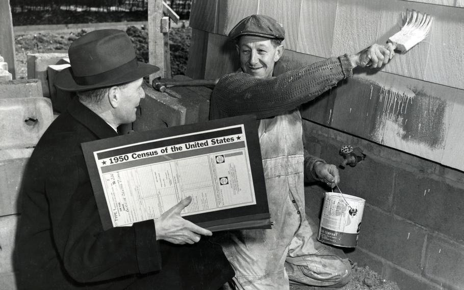 In Roosevelt, NY, census enumerator Thomas Cronin interviews Thomas Weckenman while Weckenman finishes off his new Cape Cod home with a coat of paint on April 1, 1950. 