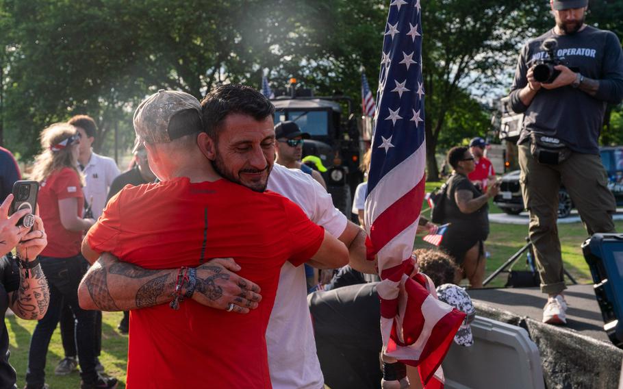 Two men hug each other with an American flag