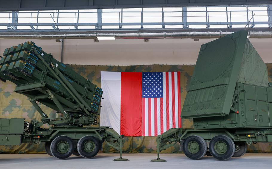 Polish and American flags hang between a Patriot air defense missile system 