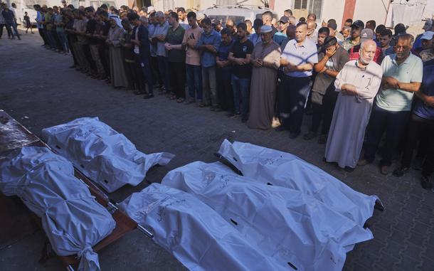 Bodies of people, covered in tarps, are on the ground in a street. They were killed in an Israeli military strike.