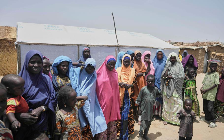 Women and children standing in a camp.