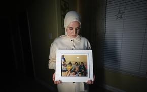 FILE - Maryam Kamalmaz hold a photo of her father with some of his 14 grandchildren in Grand Prairie, Texas, Jan. 17, 2024.  U.S. officials have developed specific and highly credible intelligence suggesting that Majd Kamalmaz, an American citizen who disappeared seven years ago while traveling in Syria has died, Maryam Kamalmaz said Saturday, May 18.  (AP Photo/Julio Cortez, File)