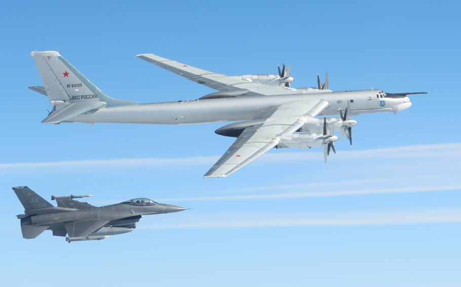 Fighter jet flies near a larger plane with propellers.