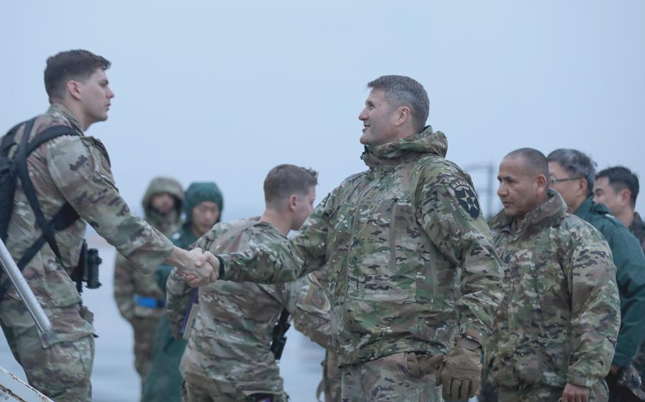 An Army major greets soldiers.