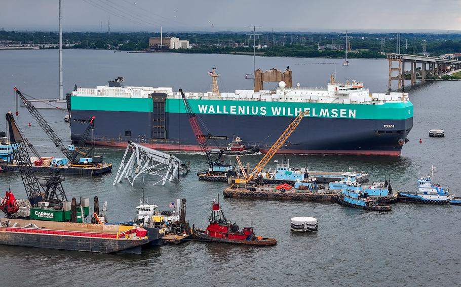 The vehicle carrier Tosca passes through an open section of the Federal channel as crane barges continue work on clearing the debris from the Francis Scott Key Bridge more than two months after the catastrophic collapse.