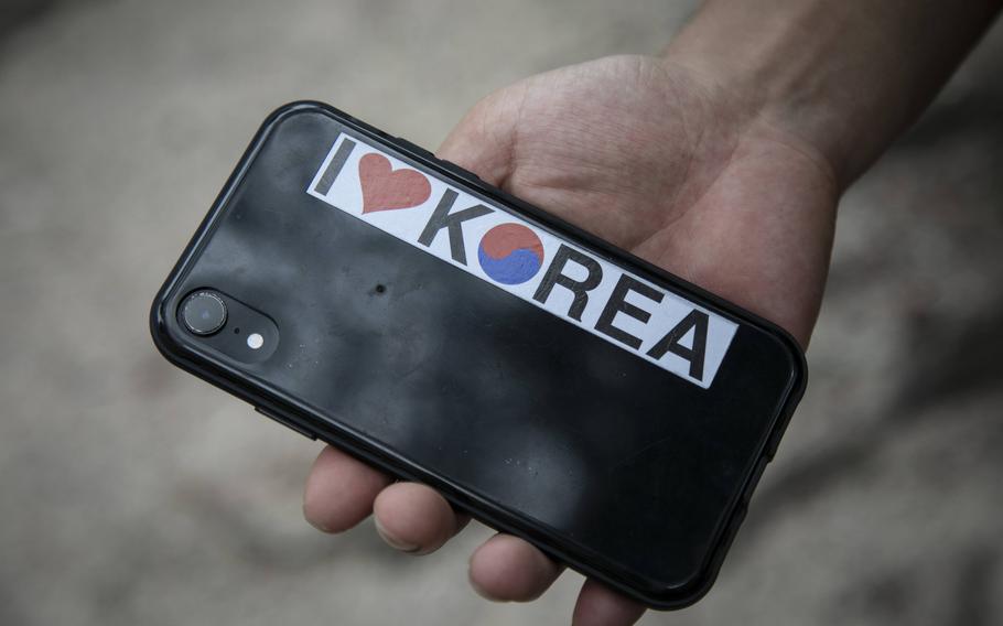 Kim Kang-woo shows the "I Love Korea" sticker in the back of his phone near his mother's apartment in Seoul on July 12, 2022.