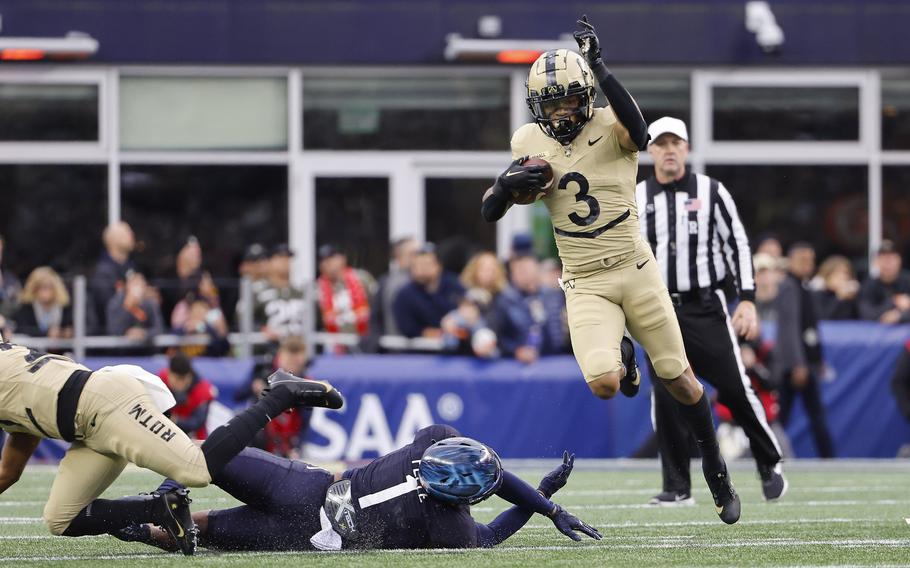 Army’s Ay’Jaun Marshall leaps over Navy’s Dashaun Peele (1) during the first quarter of an NCAA football game at Gillette Stadium Saturday, Dec. 9, 2023, in Foxborough, Mass.