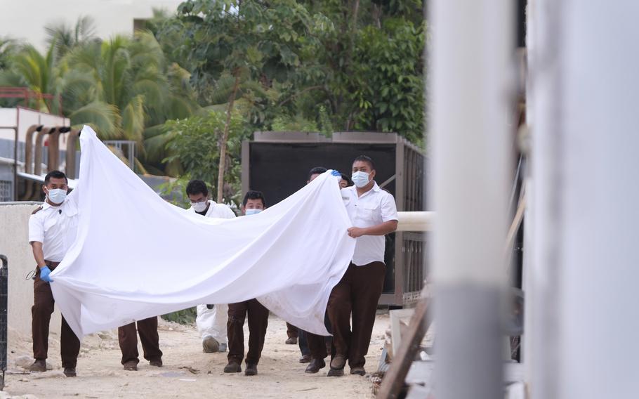 Police hold a bed sheet in an attempt to block onlookers after a fatal, armed confrontation close to a hotel near Puerto Morelos, Mexico, Nov. 4, 2021. Mexico will deploy a battalion of National Guard troops to its Mayan Riviera in the wake of a spate of shootings that have put the crown jewel of the country’s tourism industry on edge, Defense Secretary Luis Cresencio Sandoval announced Nov. 17, 2021.