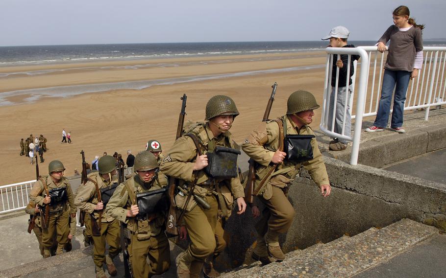 Children watch as  re-enactors from southern England climb up from Omaha Beach in Normandy, France. 