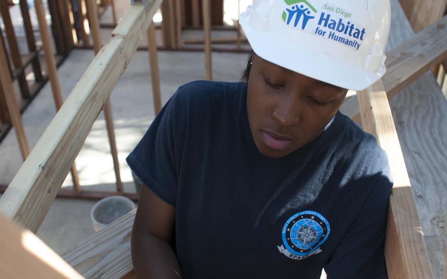 Mass Communication Specialist 2nd Class Shawnte Bryan helps build a roof during a community service event with the non-governmental organization, Habitat for Humanity. 