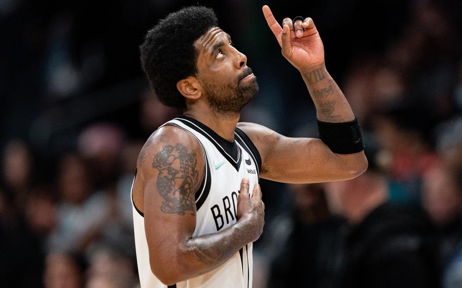 The Brooklyn Nets’ Kyrie Irving looks up and points to the sky during a game on March 8, 2022, in Charlotte, N.C. Irving will become the first beneficiary of the New York City mayor’s change of heart on vaccine mandates when he plays his first home game of the season Sunday at the Barclays Center. 