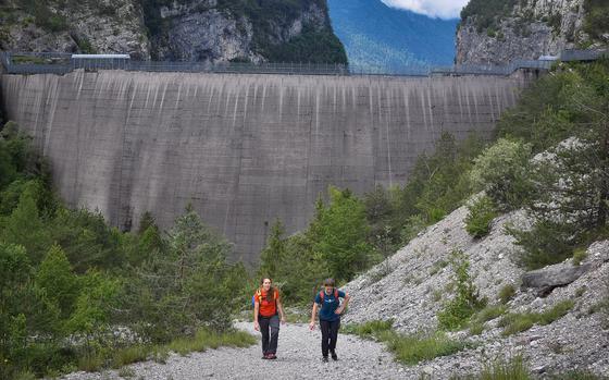 Italian visitors to the Vajont Dam hike up the rock-strewn pathway after checking out the dam up close. People still regularly come to the site decades after a disaster that killed more than 1,900 residents of nearby villages.