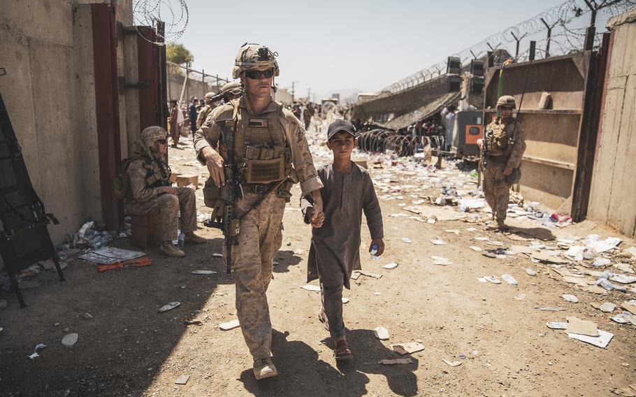 A U.S. Marine escorts a young evacuee at Hamid Karzai International Airport in Kabul, Afghanistan, Aug. 24, 2021. 