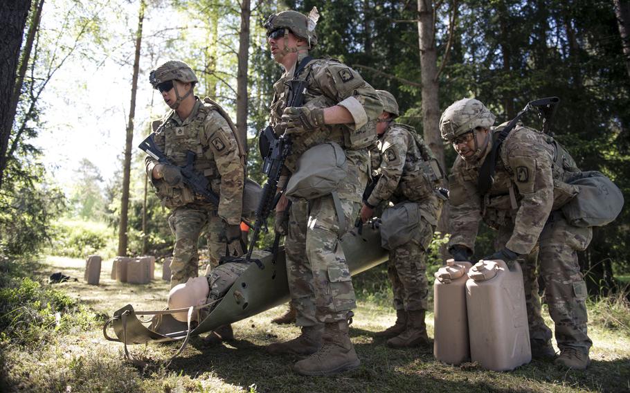 A team of soldiers carries a casualty dummy and jerry cans.