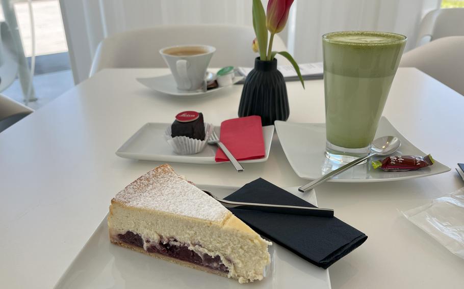 A slice of cheesecake, a chocolate confection, a matcha drink and a coffee drink sit on a table at Cafe Leitz.