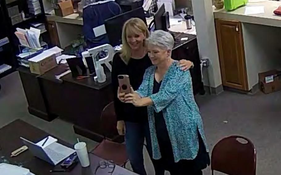 In this Jan. 7, 2021, image taken from Coffee County, Ga., security video, Cathy Latham (right) appears to take a selfie with a member of a computer forensics team inside the local elections office. Latham was the county Republican Party chair at the time. The computer forensics team was at the county elections office in Douglas, Ga., to make copies of voting equipment in an effort that documents show was arranged by Sidney Powell and others allied with then-President Donald Trump. 