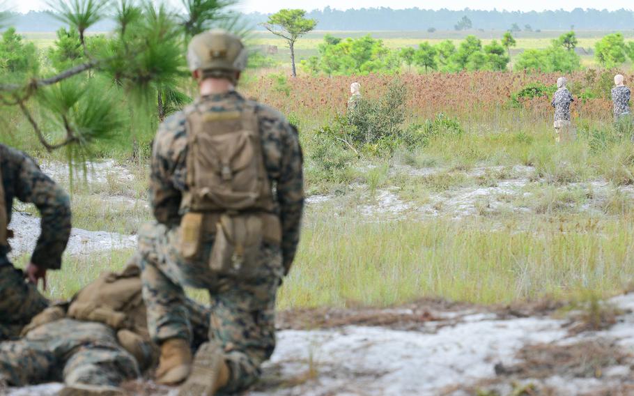 Marine infantry students look out at enemy target robots during training at Camp Lejeune, N.C., on Aug. 27, 2021. The students were practicing an ambush during an initial infantry training pilot program meant to drastically change the way the Corps trains its infantrymen. The pilot program expands infantry training from nine to 14 weeks and places Marines in 14-person squads under a single instructor.