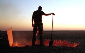 An American servicemember in the Saudi Arabian desert in 1991 tends a burning trash pit.
 