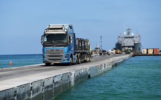 A DoD-contracted driver transports humanitarian aid from the U.S. Army vessel LSV-5, across the Trident Pier, and onto the beach in Gaza, June 20, 2024. The temporary pier, part of the Joint Logistics Over-the-Shore capability, enables the maritime delivery of international humanitarian aid to the citizens of Gaza. (U.S. Navy photo by Mass Communication Specialist 1st Class Jordan KirkJohnson)