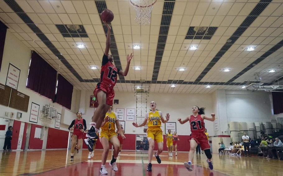 Nile C. Kinnick's KaMiyah Dabner drives to the basket ahead of Robert D. Edgren's Keria Marrero and Kaitlyn Willets and teammate Jasmine Pho during Saturday's DODEA-Japan girls basketball game. The Red Devils won 41-16.