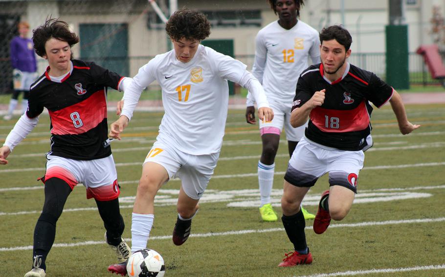 Yokota's Luke Harbert dribbles between E.J. King's N.J. Reed and P.J. Lampley during Wednesday's Boys Division II soccer match. The Panthers won 5-3.