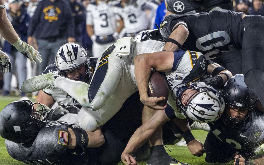 Army’s defense grabs Blake Horvath by the legs and the shoulder pads.