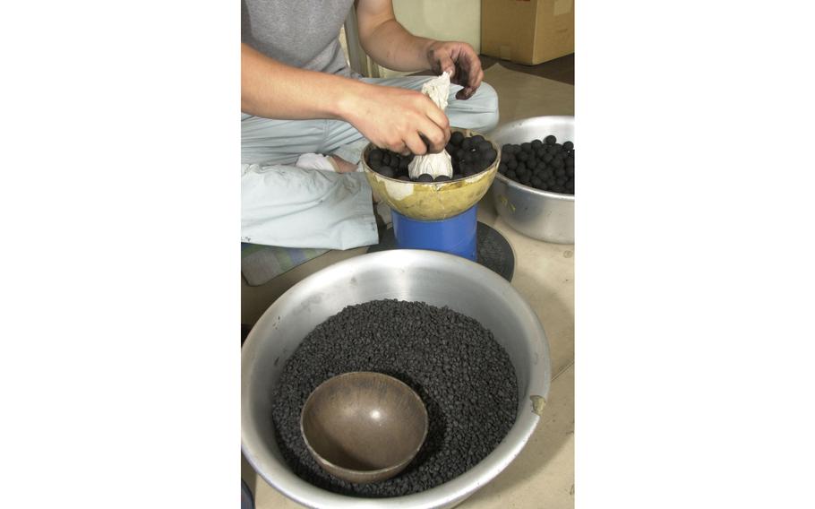 After the outer layer of black powder balls has been laid in, the inside layer is wrapped in paper, placed into the center and formed into the pattern that the fireworks will blow up as.