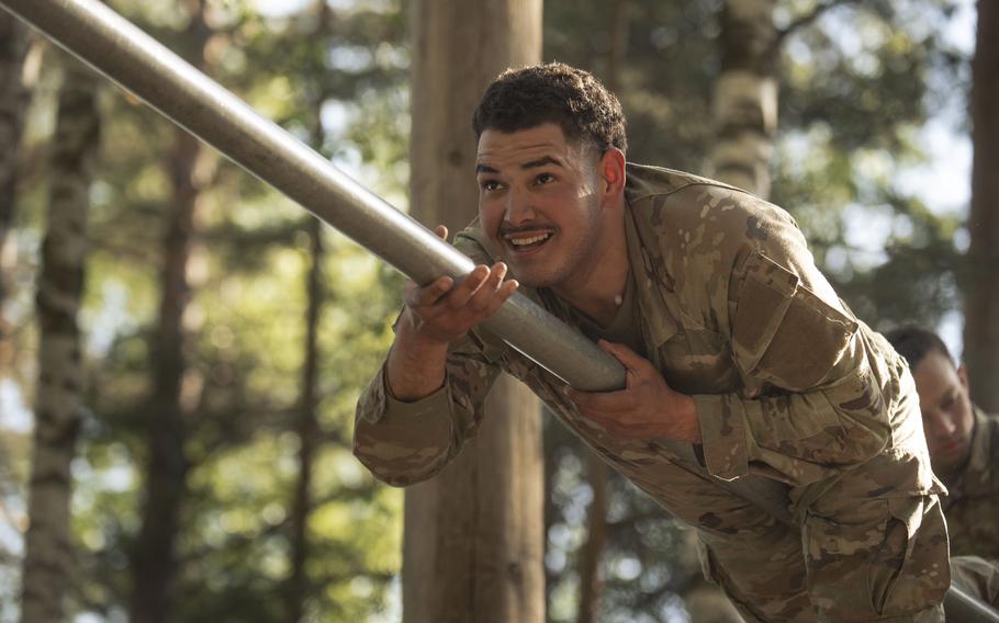 A soldier gripping a pole during an obstacle course.