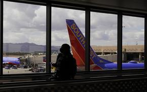 A passenger walks past a Southwest Airlines plane at Sky Harbor International Airport in Phoenix, March 26, 2021. AT&T and Verizon have agreed to delay the launch of a new slice of 5G service by two weeks after airlines and the nation's aviation regulator complained about potential interference with systems on board planes. 
