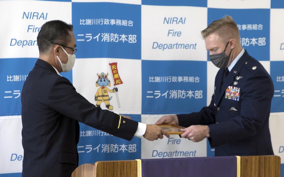 Air Force Lt. Col. Matthew Schlittler receives a certificate of appreciation from Nirai Fire Chief Keiichi Teruya at the firehouse in Kadena, Okinawa, Thursday, Dec. 1, 2022. 